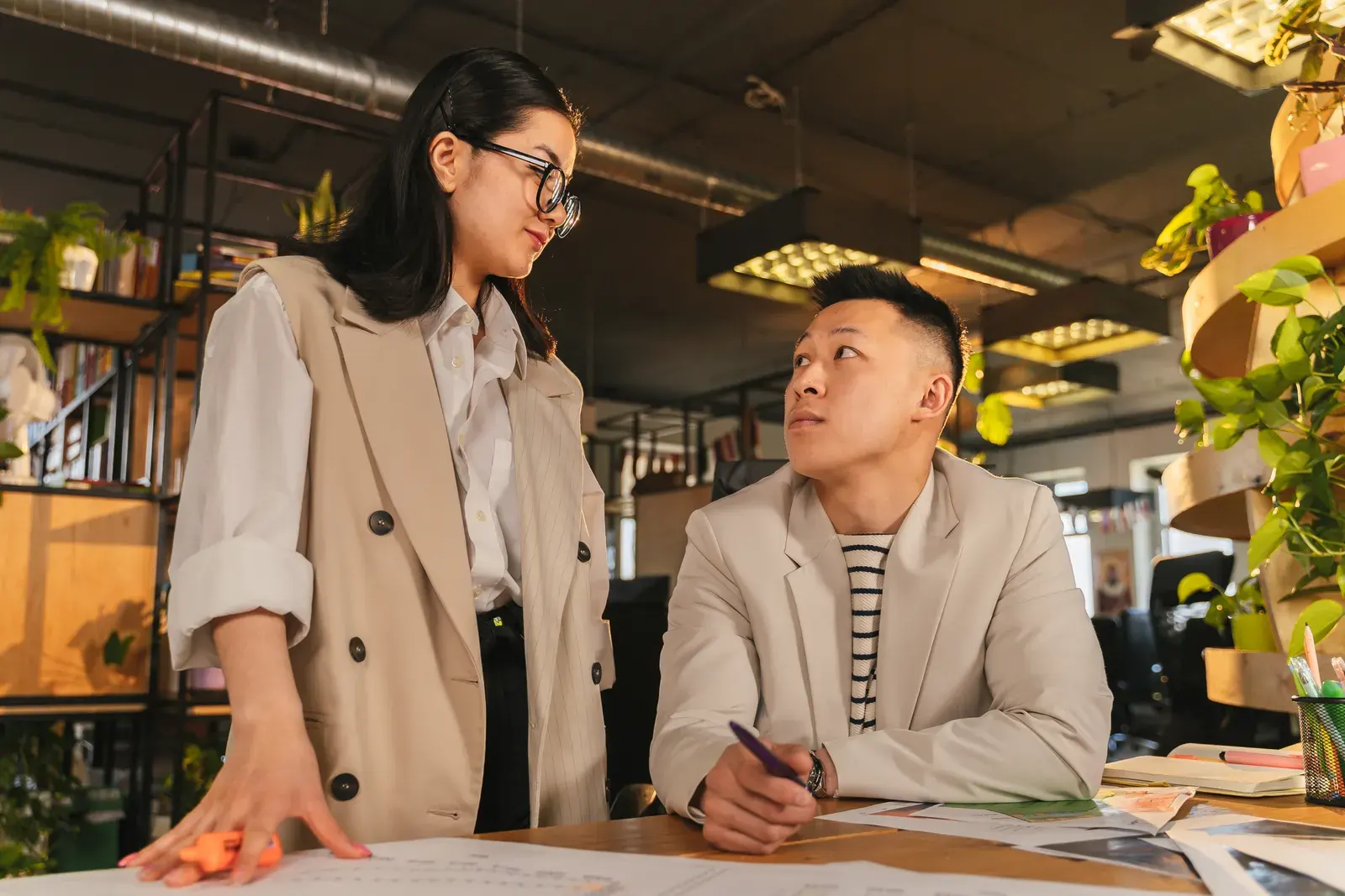 Two business colleagues collaborating at a modern office desk. Engaging discussion and teamwork.