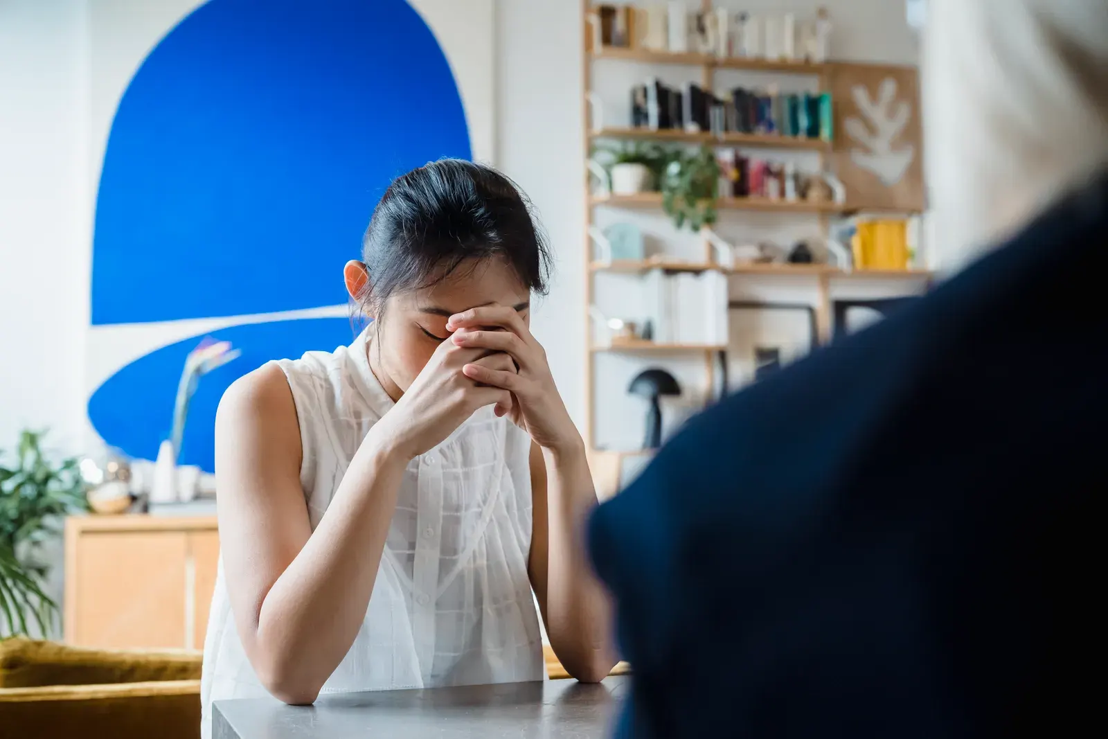 A woman appears deep in thought during an indoor therapy session.