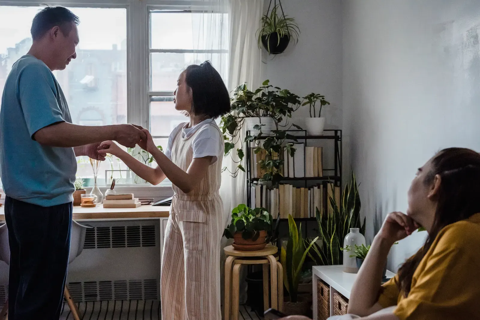 A father and daughter enjoying a dance inside a warm, plant-filled home, illustrating familial love.