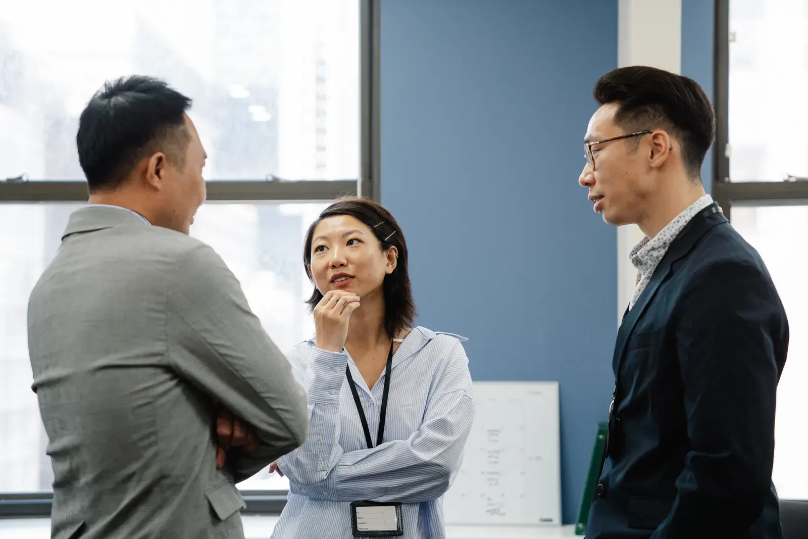 Three business colleagues engage in a thoughtful discussion in a modern office setting.