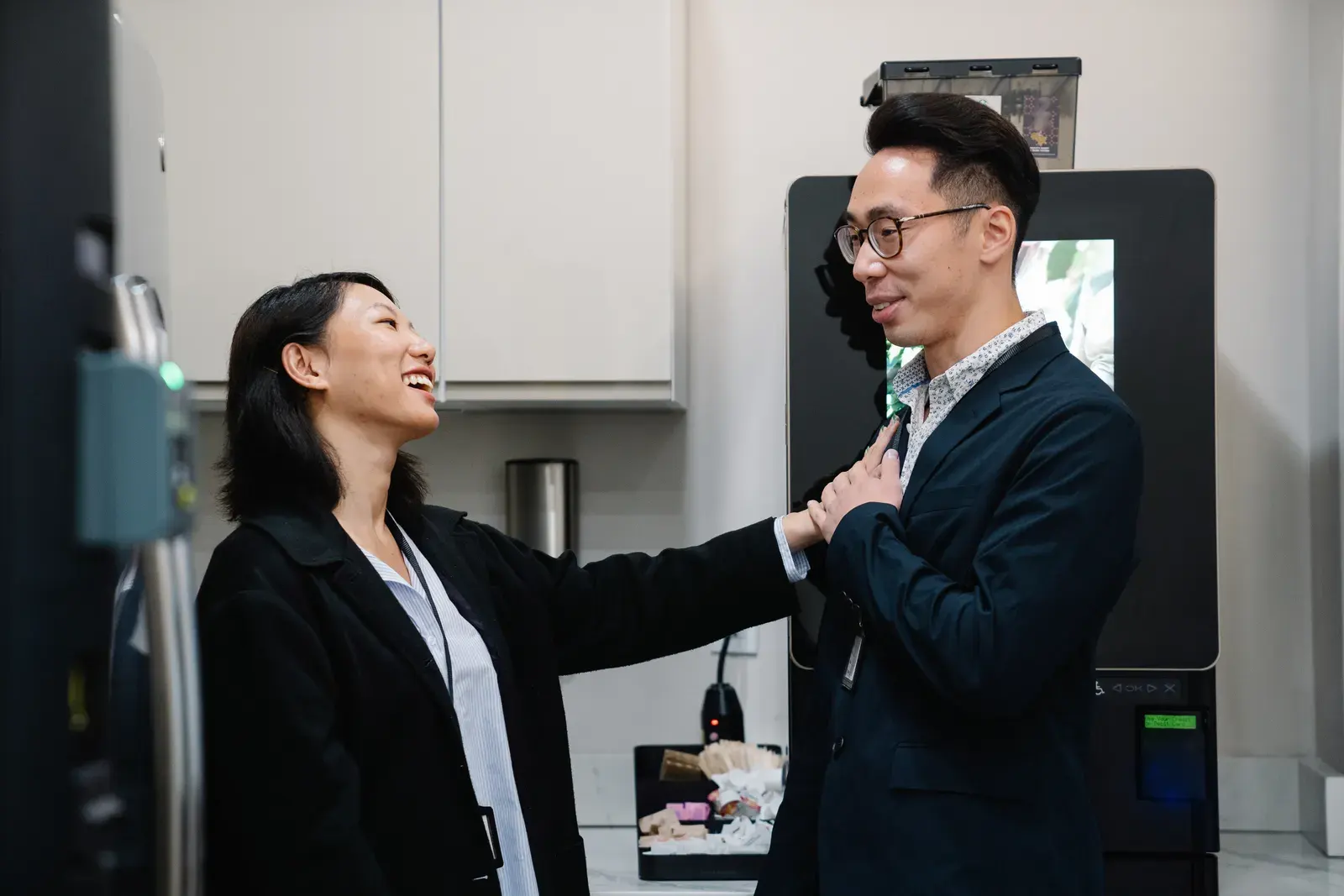 Two colleagues laughing and chatting during a break at the office.