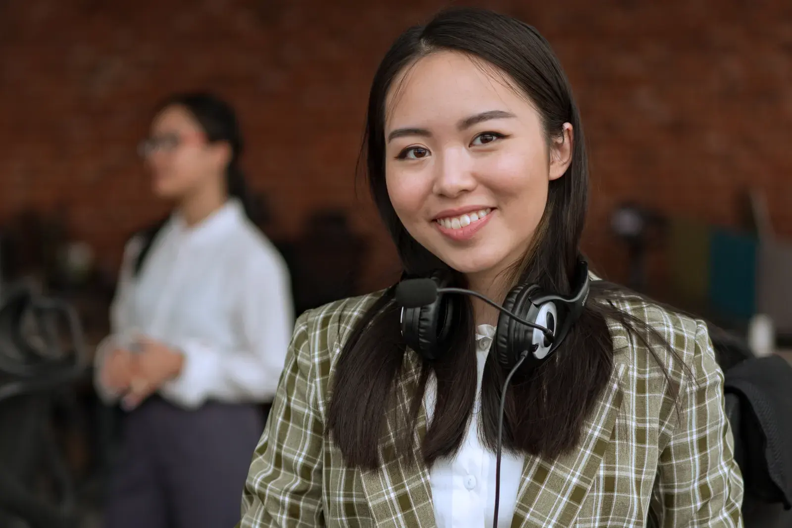 Smiling professional woman wearing a headset in an office environment, exuding confidence.