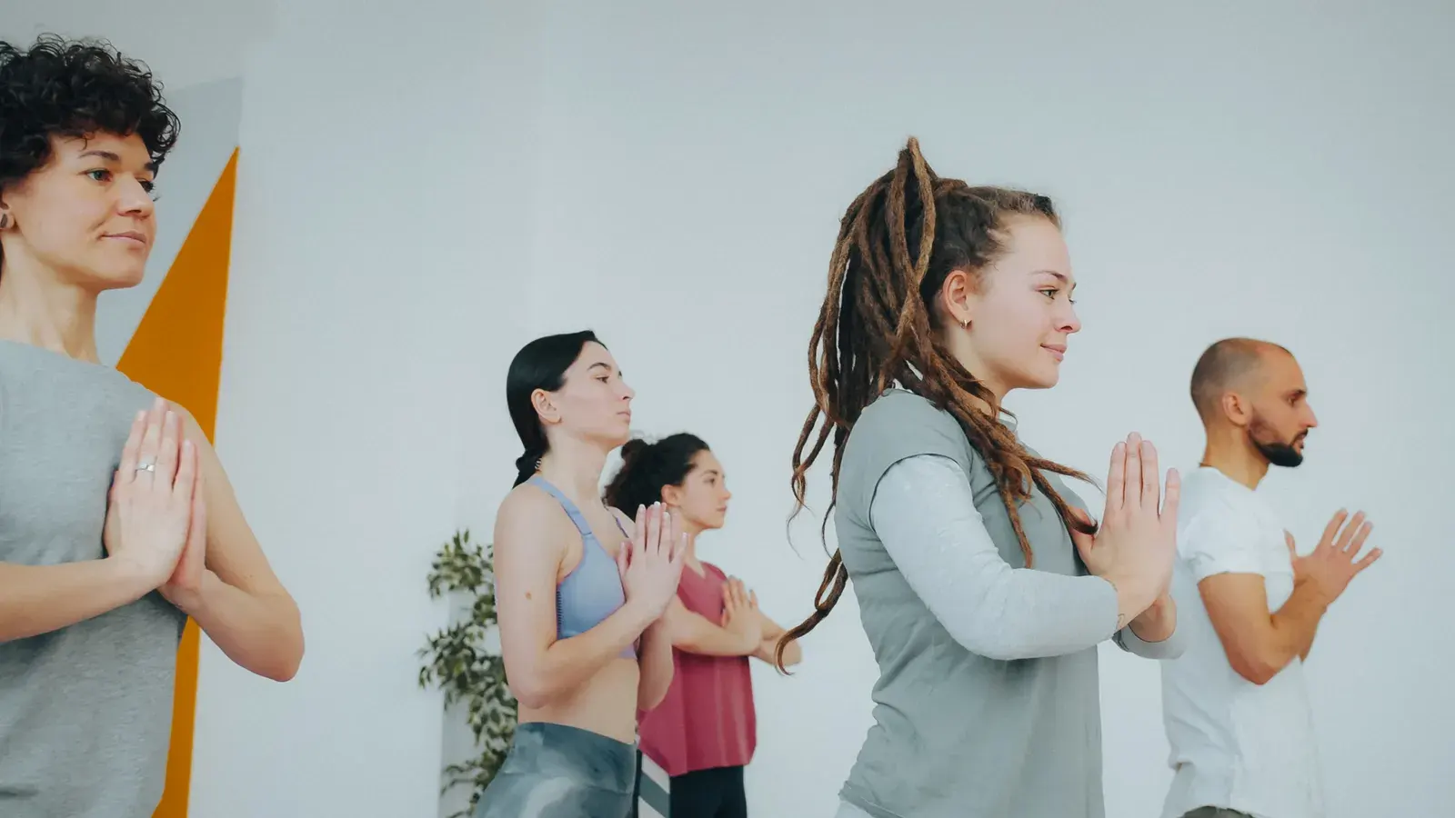 Diverse group of adults practicing yoga indoors, maintaining focus and calmness.