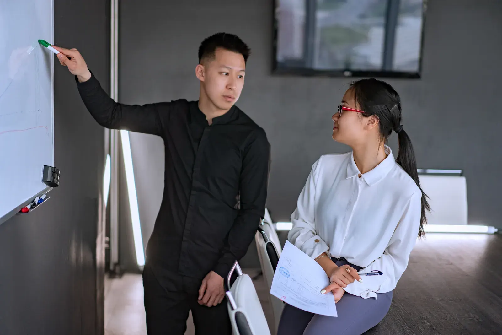 Professional team discussing ideas at a whiteboard in a modern office setting.