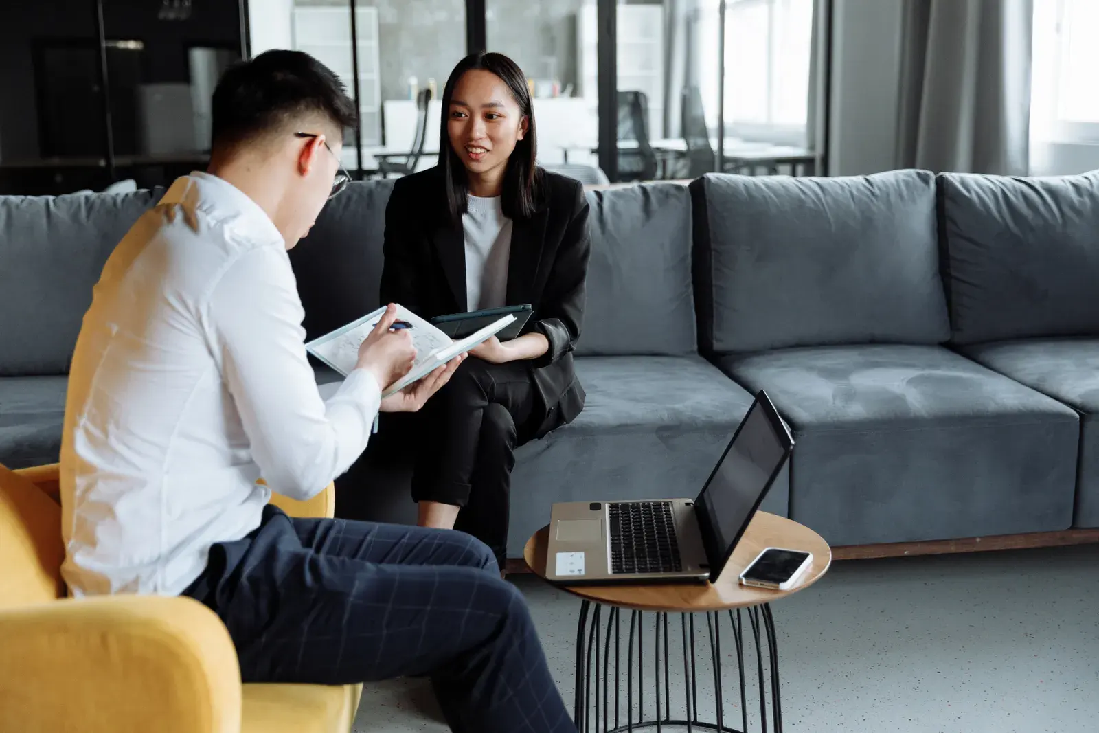 Two professionals collaborating in a modern office setting, discussing ideas with technology.