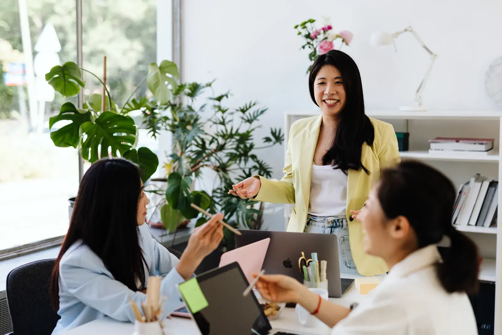 Three women engage in a lively brainstorming session in a modern office setting.