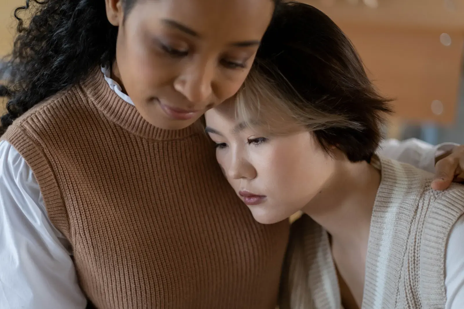 A tender moment of support between two women indoors, conveying care.