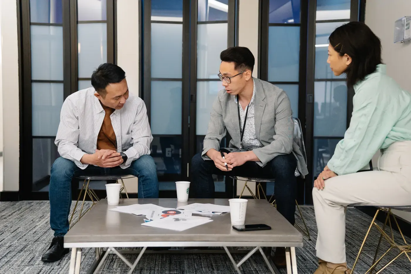 Three colleagues engaging in a team discussion in a modern office environment. Ideal for business and teamwork concepts.