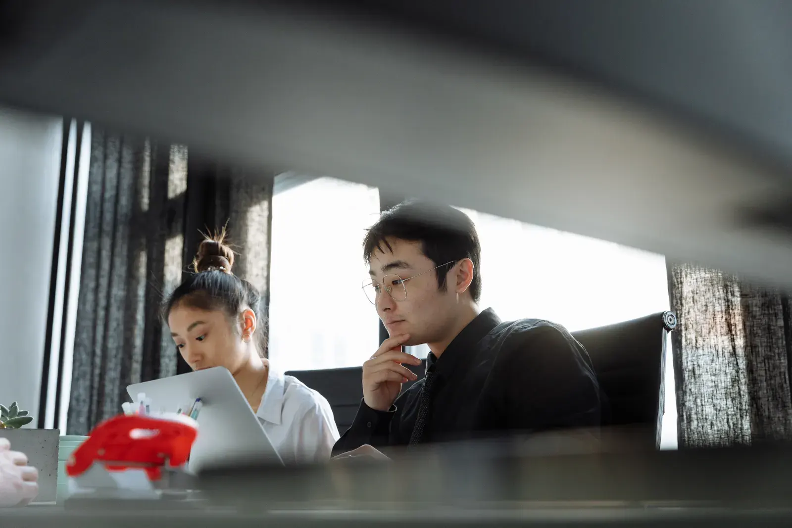 Two professionals working together in an office, deeply focused on their tasks.