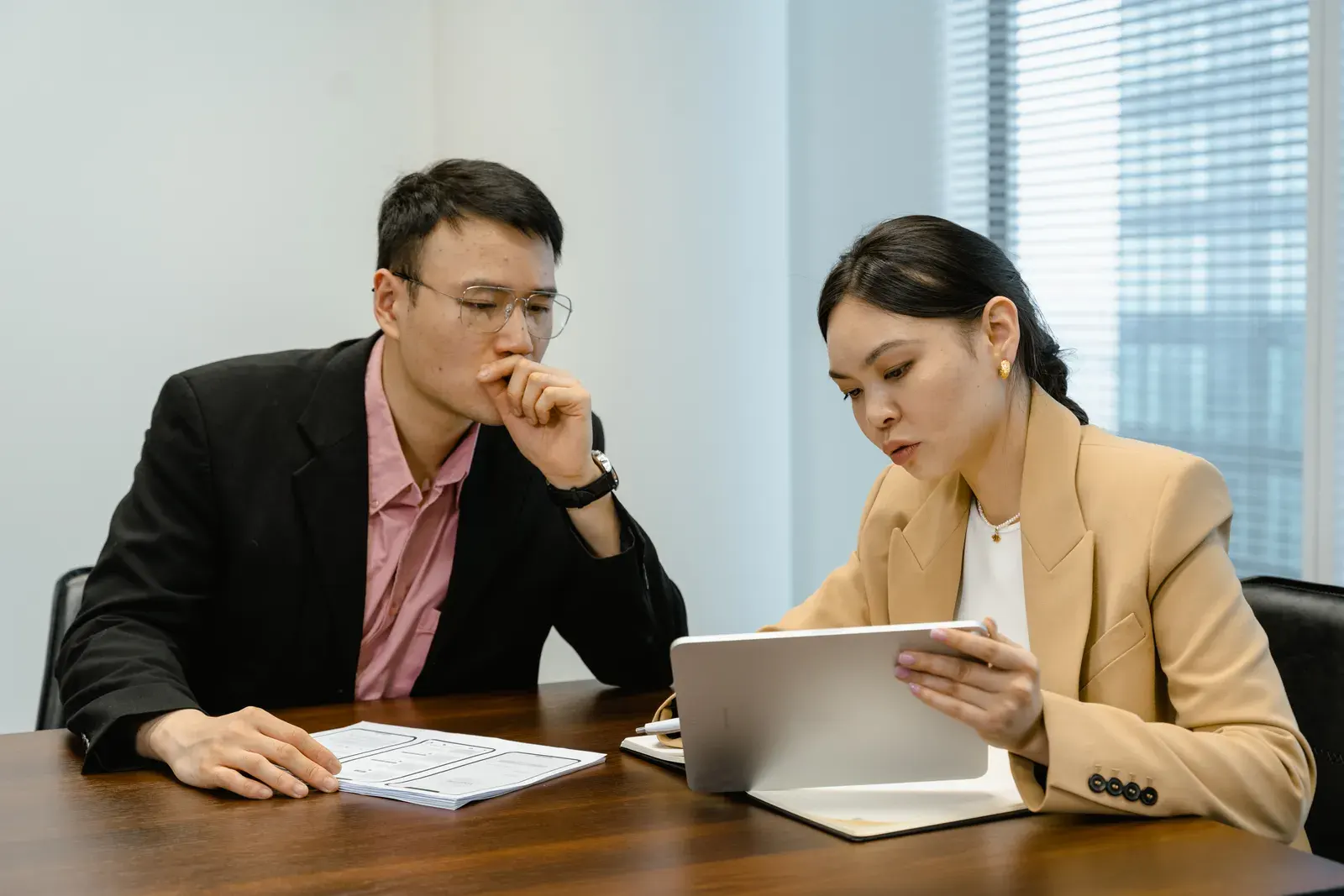 Business colleagues discussing at a meeting with a digital tablet. Indoor setting with focus on collaboration.
