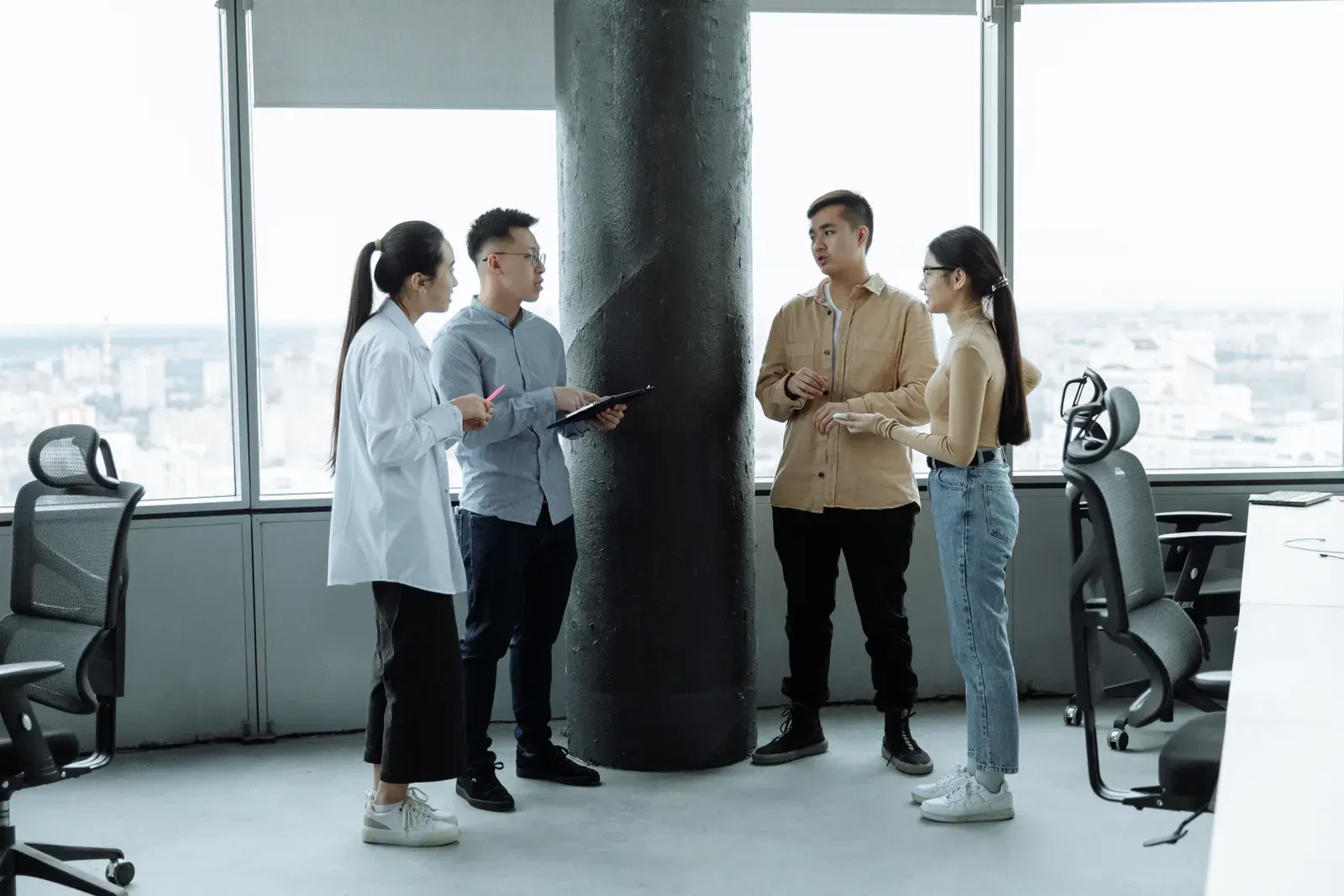 Diverse team discussing ideas in a modern office with city view, fostering collaboration.