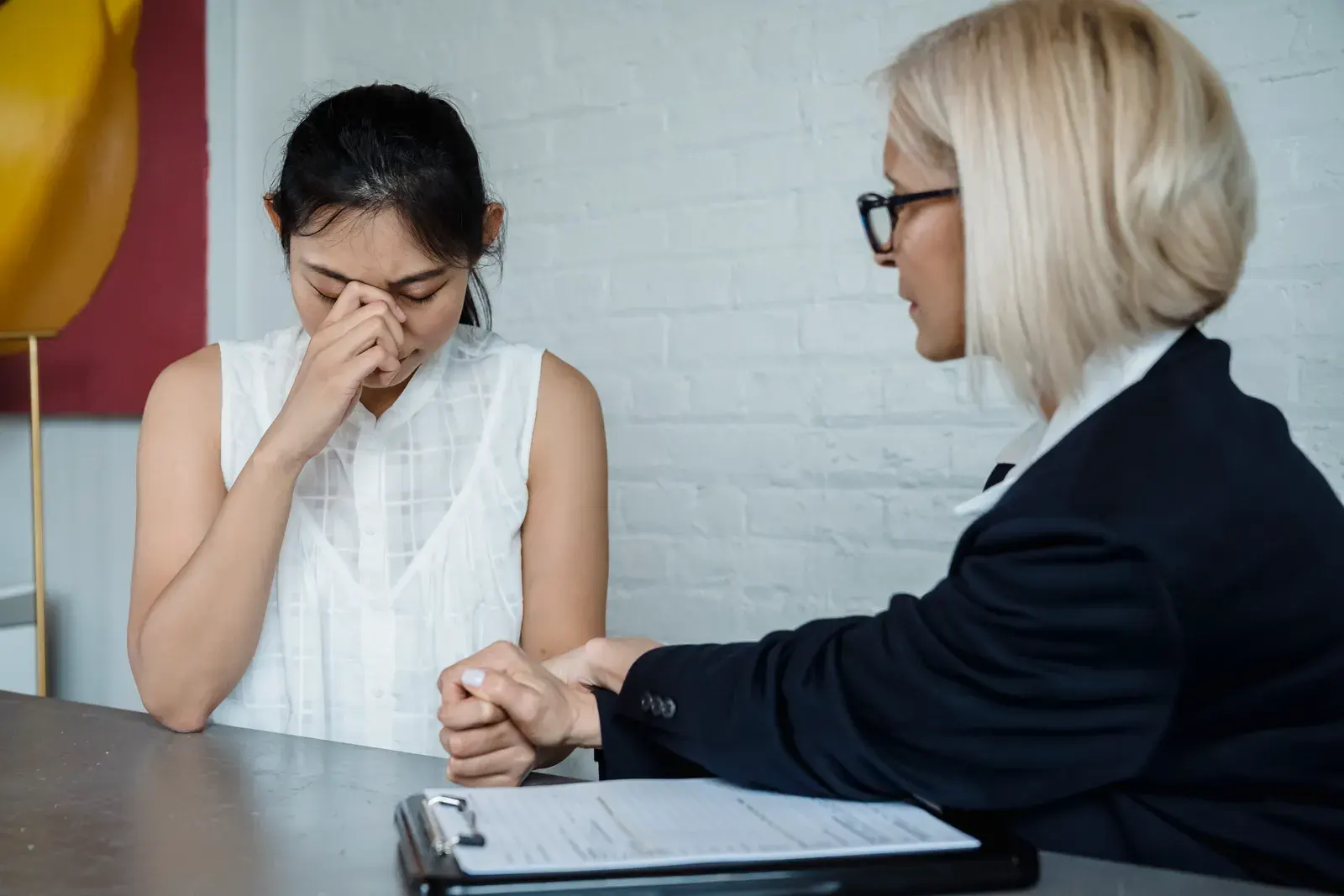 Emotional therapy session featuring a supportive female therapist helping a worried young woman.