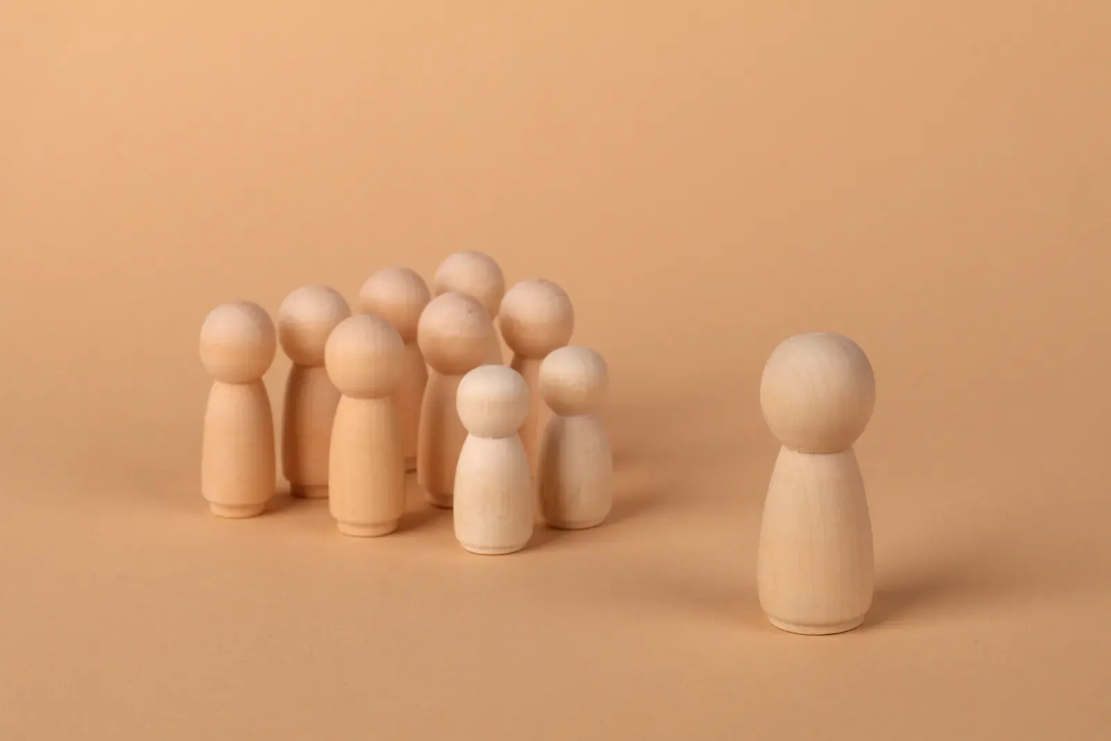 Minimalist image of wooden figures symbolizing social dynamics and isolation.
