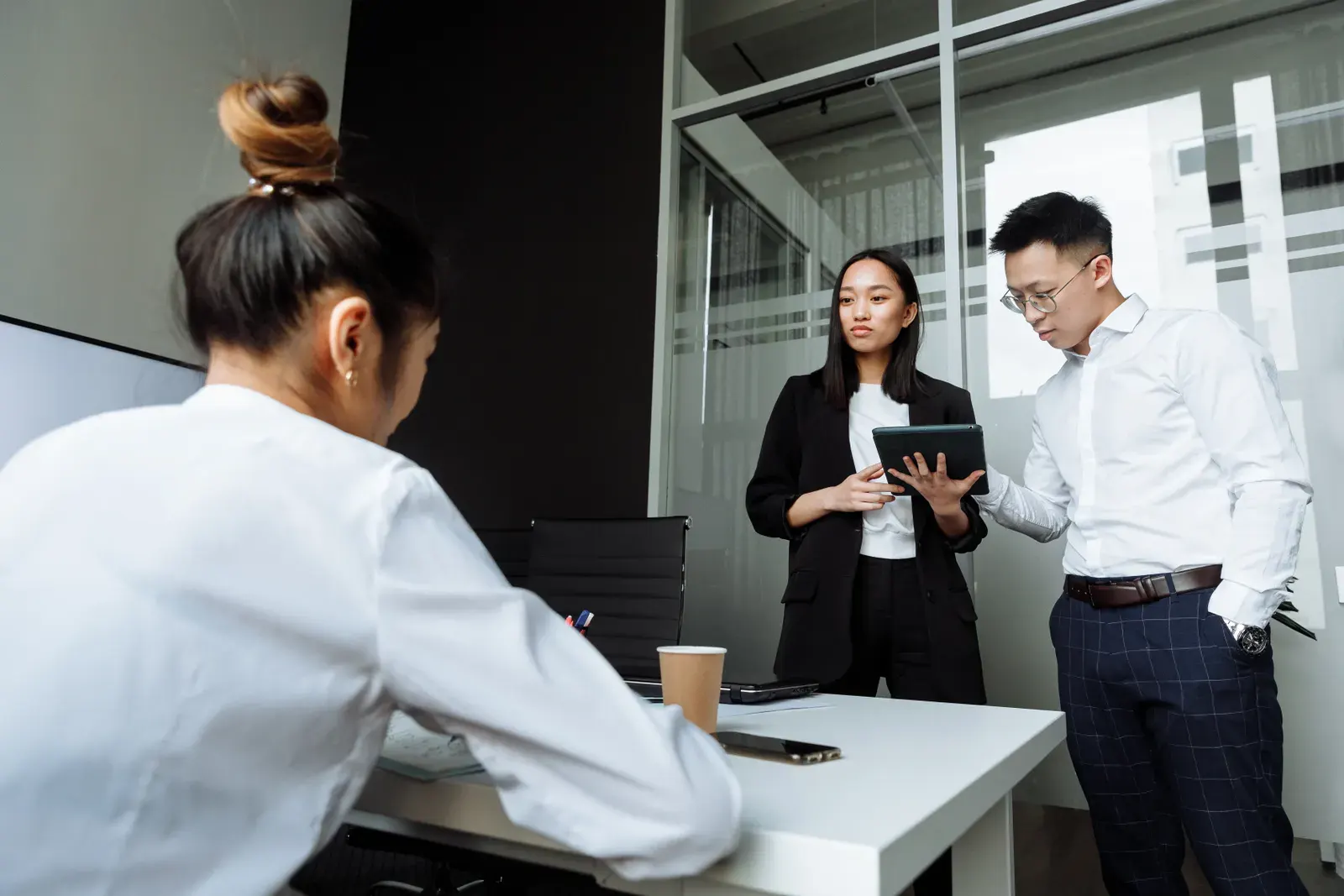 Three coworkers engaged in a discussion in a modern office setting with a focus on teamwork.