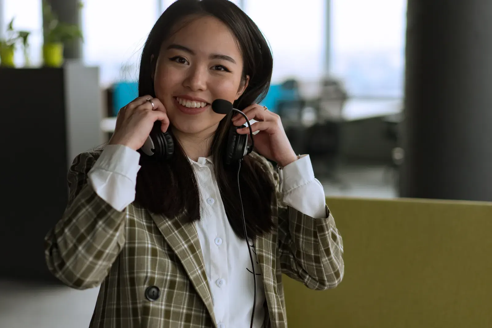 Confident woman using a headset and smiling in a modern office setting.