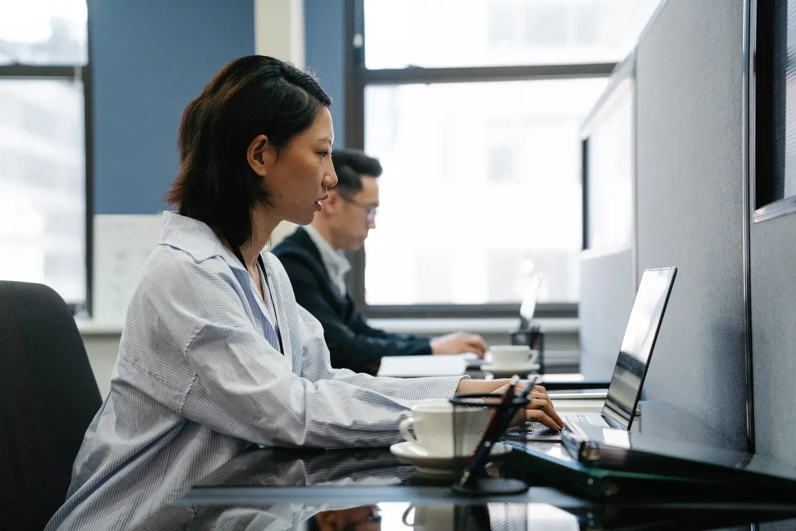 Two professionals working diligently on laptops in a modern office setup, capturing productivity and teamwork.