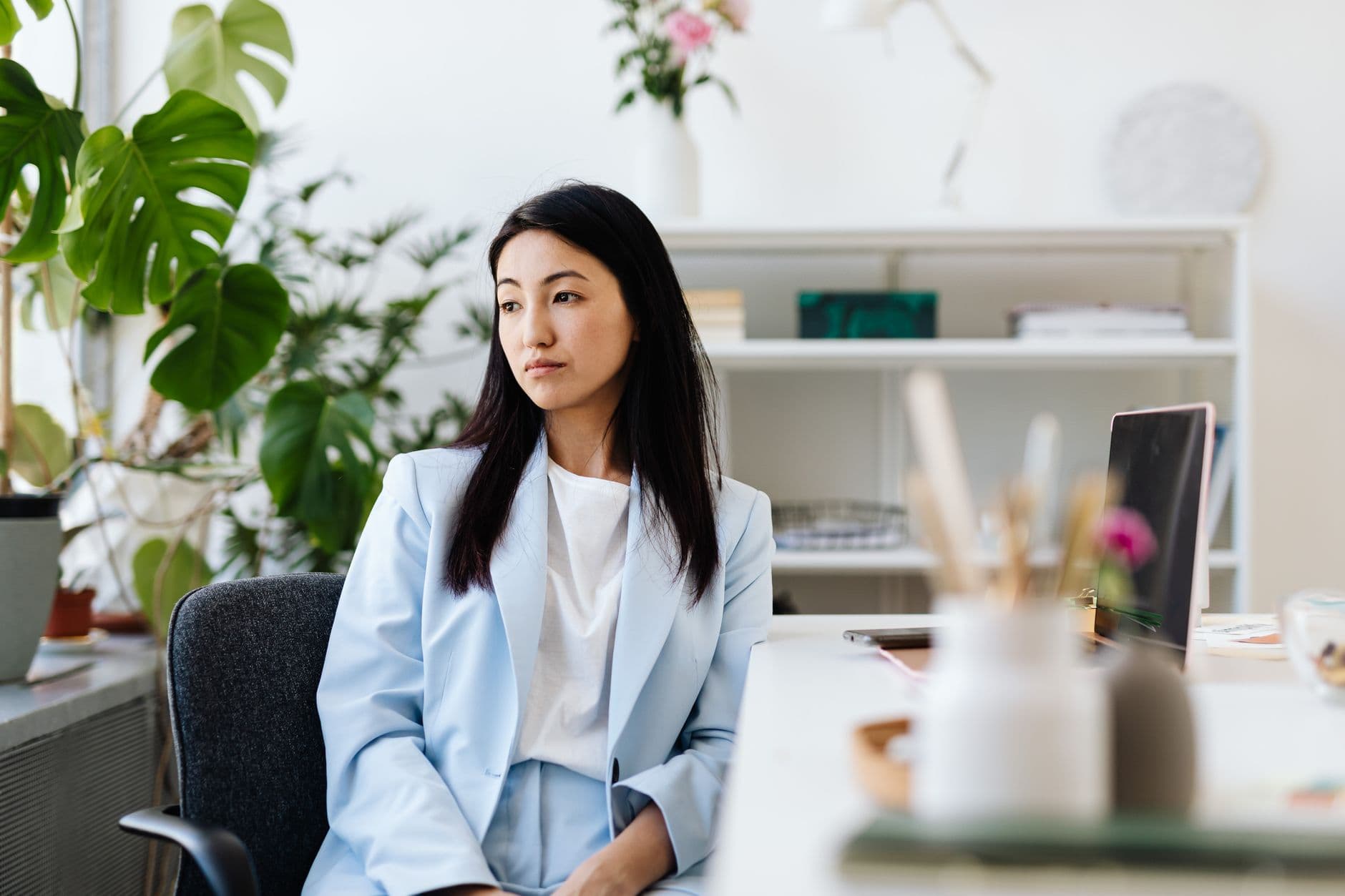 A professional pausing to reflect at her desk in a bright office